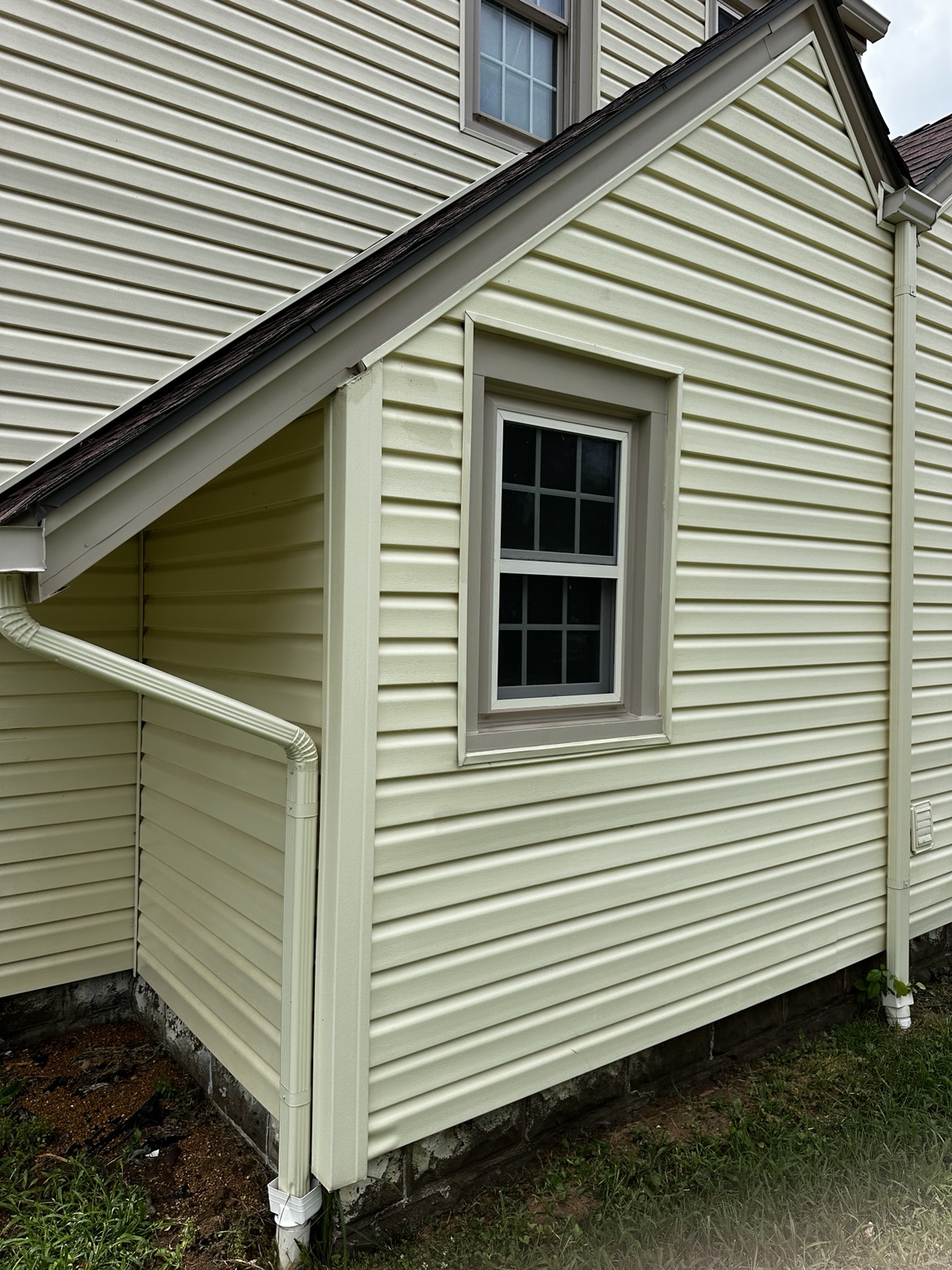 Clean vinyl siding around a window after house washing in El Dorado, Kansas