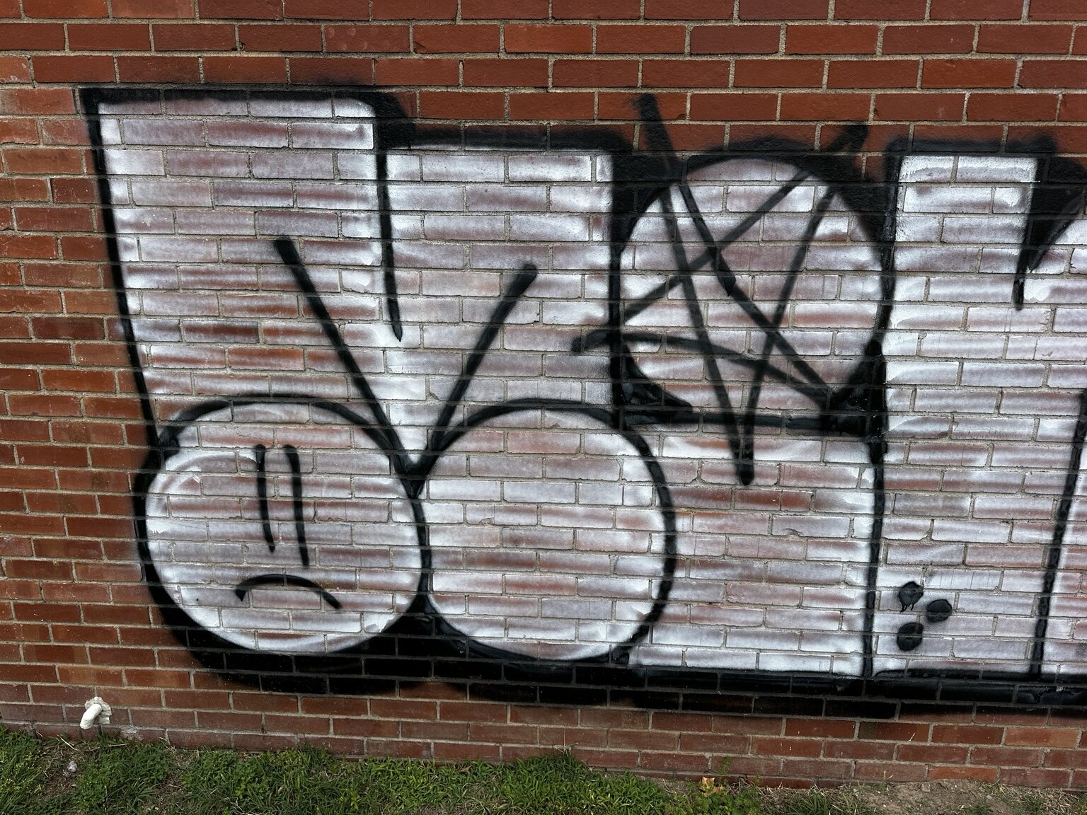 Close view of the left side of graffiti painted on brick