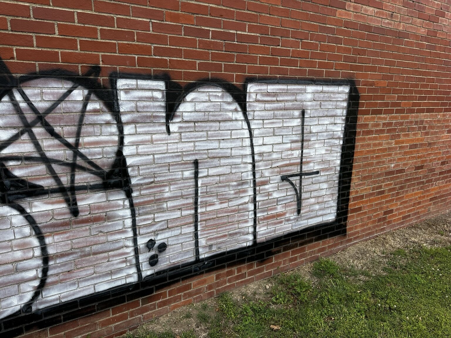 Close view of the right side of a large graffiti tag on brick